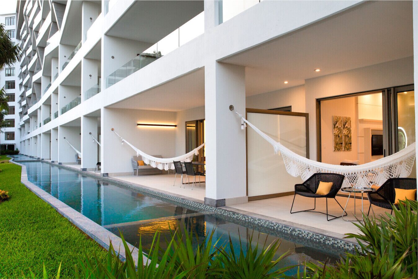 Un hôtel moderne doté d’une piscine, d’un espace extérieur aménagé et d’un hamac.