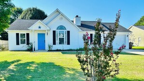 Una casa de una planta con puerta azul, una estrella en la fachada y un pequeño porche.