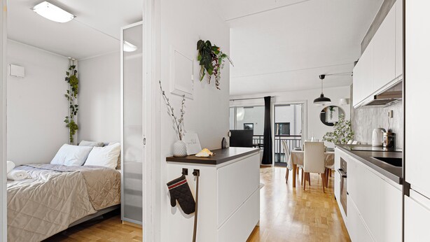 Una cocina moderna con armarios blancos, encimera de madera y zona de comedor con mesa y sillas.