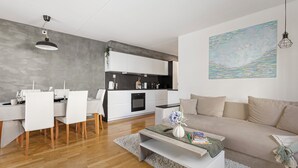 Una cocina moderna con gabinetes blancos, encimera gris y una lámpara colgante.