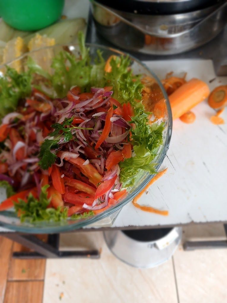 Un saladier en verre rempli d’une salade composée de légumes et de feuilles vertes.