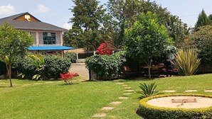 A well-maintained garden with a lawn, a circular flower bed, and a variety of trees and shrubs. - Jafra Elephant Inn (Eldoret)