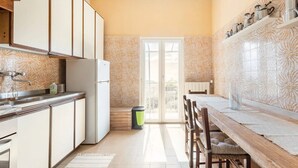 A kitchen with a refrigerator, cabinets, and a dining area with a table and chairs.