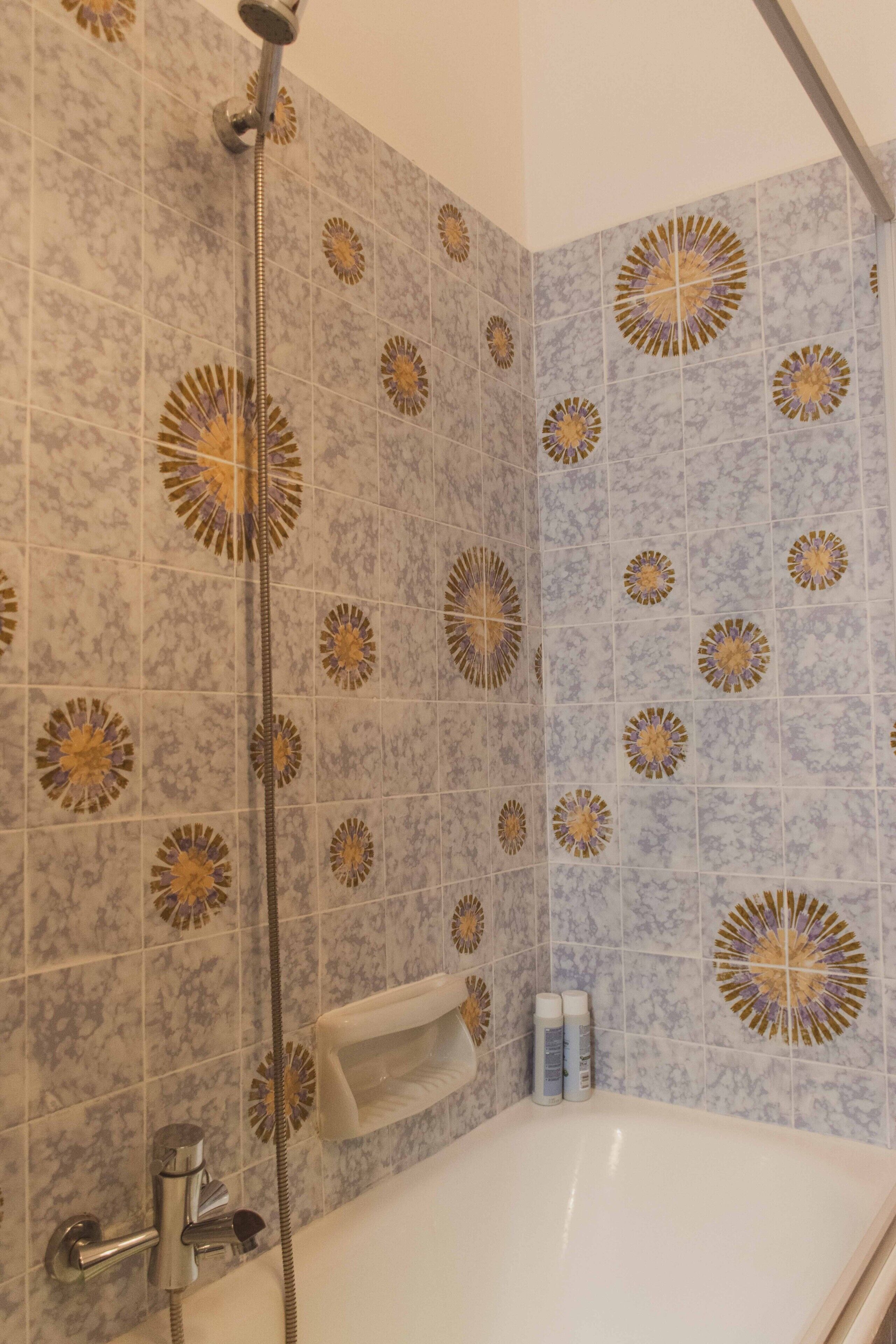 Ein Badezimmer mit Dusche, Badewanne und dekorativen Fliesen.