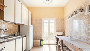 A kitchen with a refrigerator, cabinets, and a dining area with a table and chairs. - Room 'Stanza 2' with Sea View, Shared Terrace and Wi-Fi (Castiglione Chiavarese)
