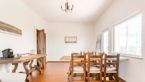 A dining area with wooden chairs and a table, a coffee machine, and a view through a window. - Room 'Stanza 2' with Sea View, Shared Terrace and Wi-Fi (Castiglione Chiavarese)