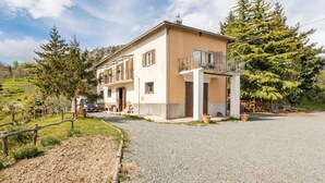 A two-story house with a balcony, a gravel driveway, and surrounding greenery. - Room 'Stanza 2' with Sea View, Shared Terrace and Wi-Fi (Castiglione Chiavarese)