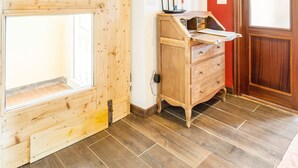 A room with wooden flooring, a wooden desk, a red wall, and a wooden door. - Room 'Stanza 1' with Sea View, Shared Terrace and Wi-Fi (Castiglione Chiavarese)