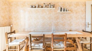 A dining area with a wooden table and chairs, a patterned wall, and shelves with kitchen utensils. - Room 'Stanza 1' with Sea View, Shared Terrace and Wi-Fi (Castiglione Chiavarese)