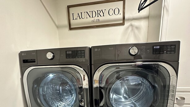 Een paar zwarte LG ThinQ wasmachines met een 'Laundry Co.' bord erboven.