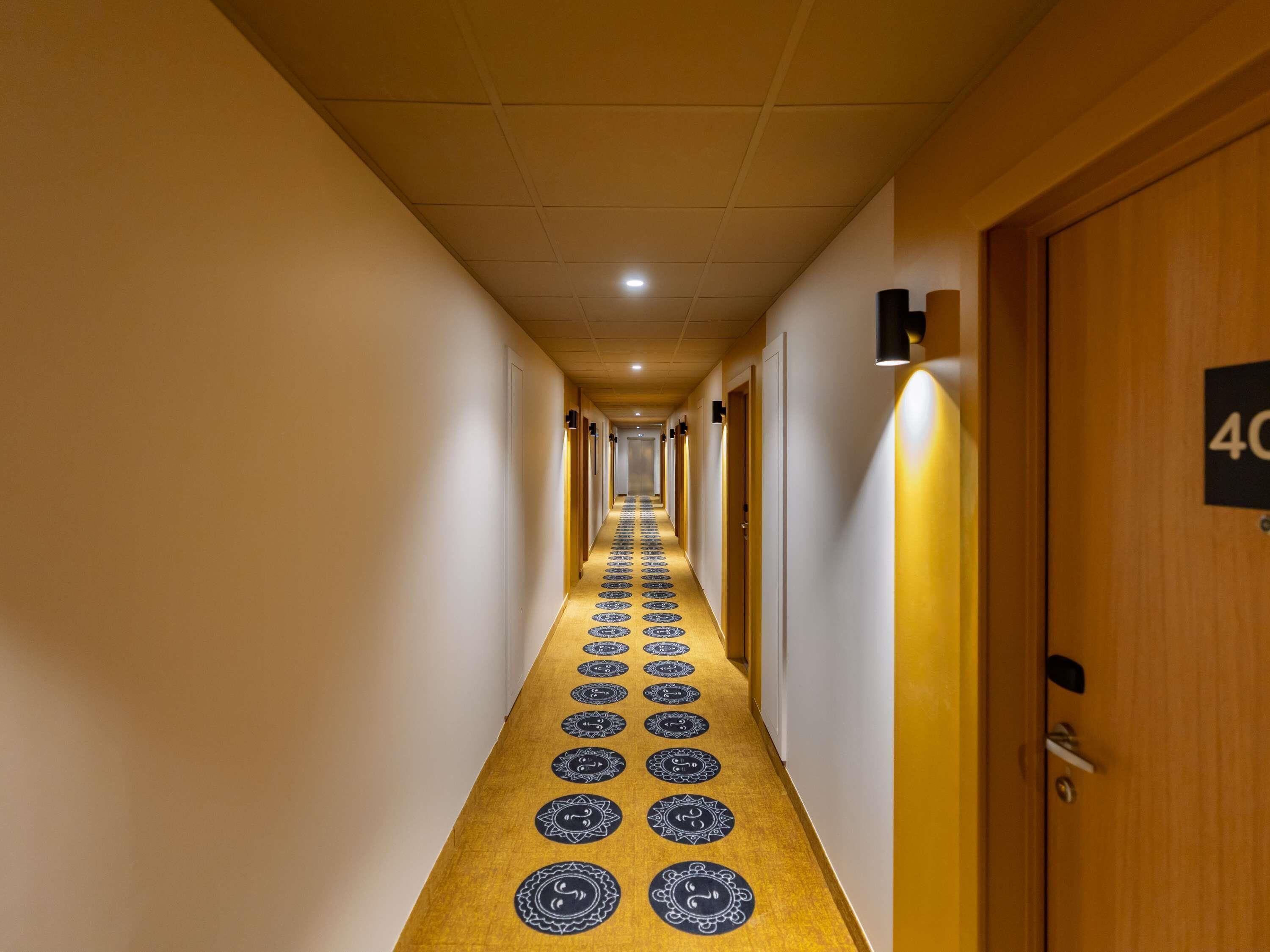 Un couloir d'hôtel avec un sol recouvert de moquette, des portes sur le côté droit et un panneau indiquant le numéro de la chambre 40.