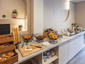 Een ontbijtbuffet met brood, fruit en dranken.