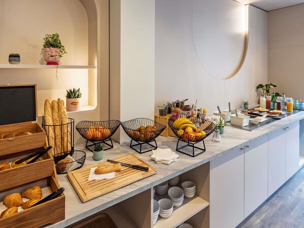 Ein FrĂŒhstĂŒcksbuffet mit Brot, Obst und GetrĂ€nken.