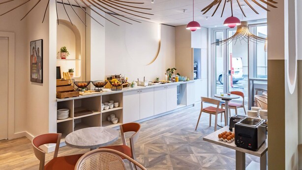 A modern kitchen with a central island, pendant lighting, and a view of the street. - ibis Styles Metz Centre (Ouverture Janvier 2026) (Metz)
