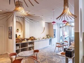 Una cocina moderna con una isla central, iluminación colgante y vistas a la calle.