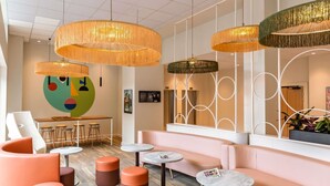 A modern interior with round tables, orange seating, and hanging rattan lamps. - ibis Styles Metz Centre (Ouverture Janvier 2026) (Metz)