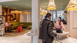 A modern interior with a checkout counter, seating areas, and decorative lighting. - ibis Styles Metz Centre (Ouverture Janvier 2026) (Metz)