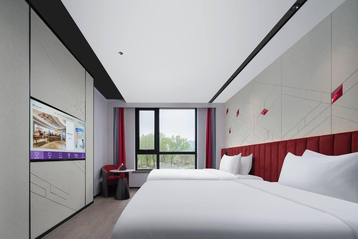 Une chambre d’hôtel moderne avec un grand lit, un petit bureau et une fenêtre donnant sur la ville.