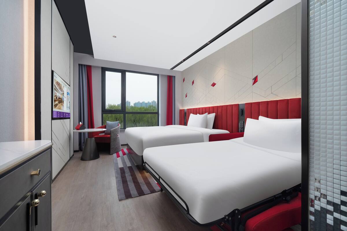 Une chambre d’hôtel moderne avec deux lits, un bureau et une vue sur la ville.
