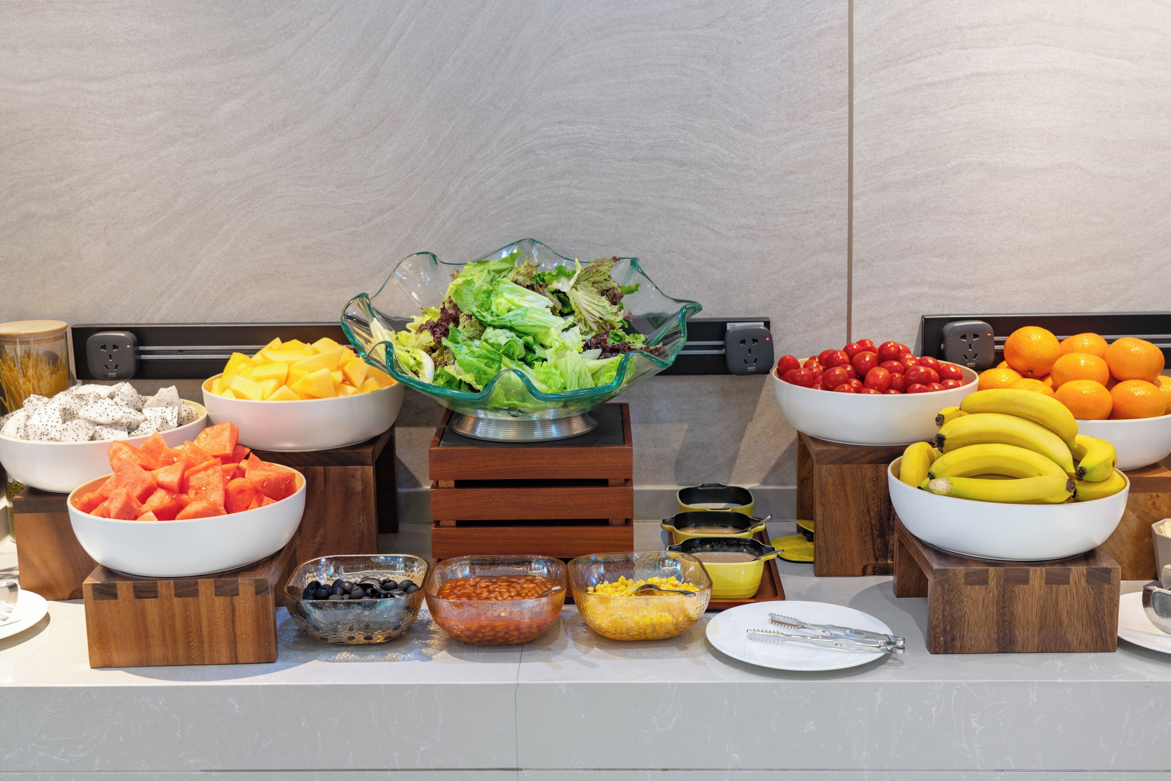 A buffet table with various food items including fruits, vegetables, and salads.