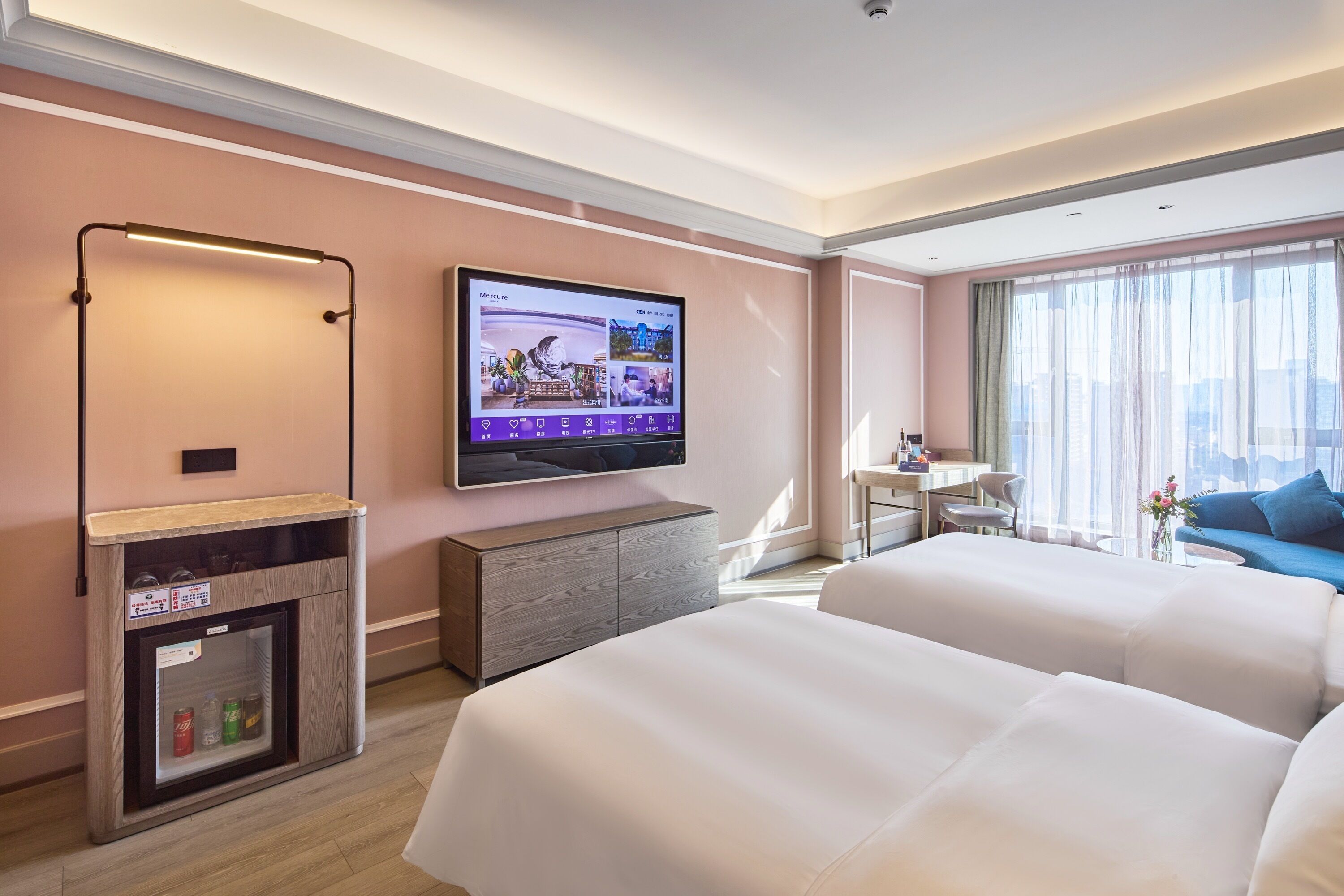 Ein Hotelzimmer mit Fernseher, Minibar, Sofa und Bett.