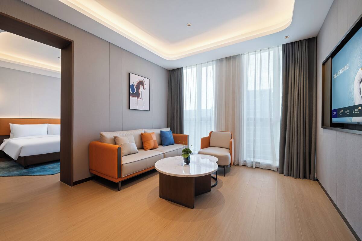 Une chambre d’hôtel moderne équipée d’un lit, d’un canapé, d’un fauteuil et d’une table basse.