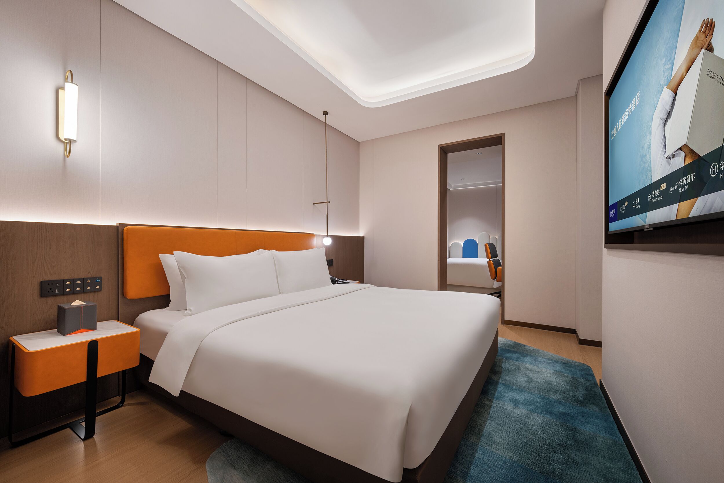 Una camera d'albergo moderna con un letto grande, un comodino, una televisione e una luce a soffitto.