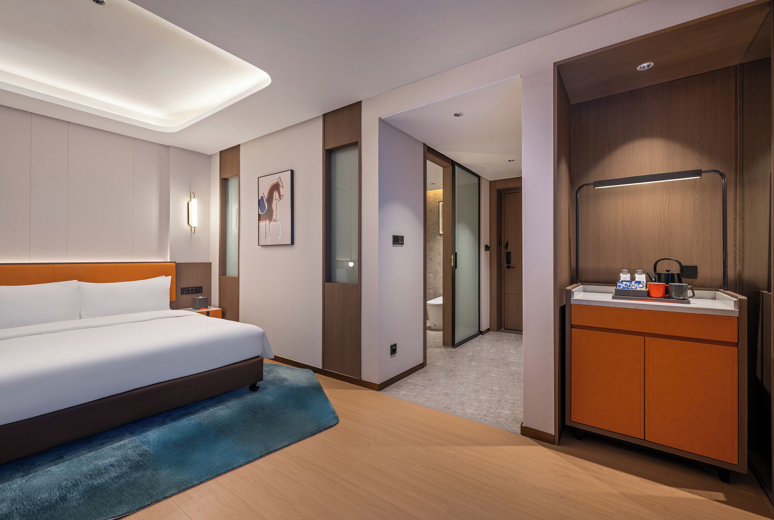A hotel room with a bed, a small bathroom, and a kitchenette.