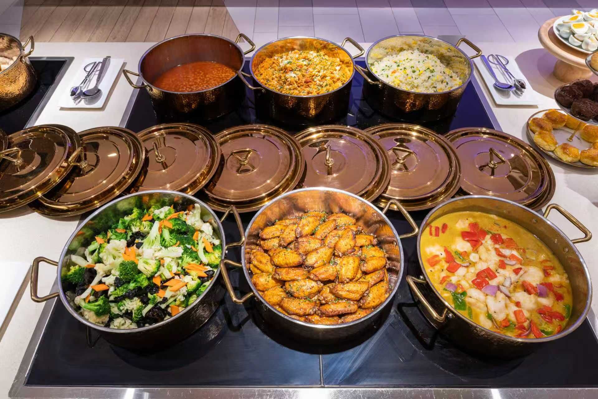 A buffet with various dishes in metal pots and bowls, arranged on a table.