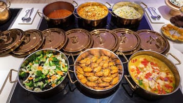 A buffet with various dishes in metal pots and bowls, arranged on a table.