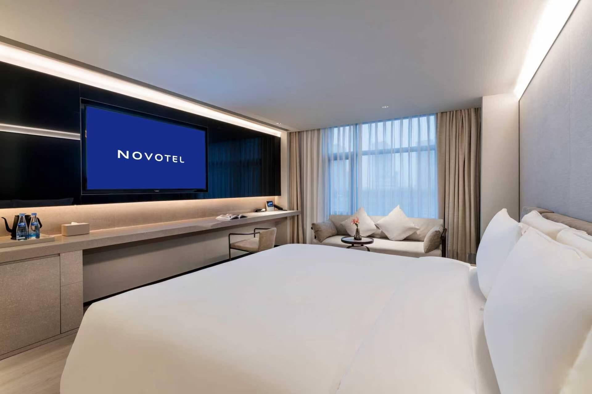 Una habitación de hotel con una cama grande, un televisor, un escritorio con una silla y un sofá.