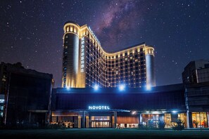 Un hôtel doté d’une façade incurvée remarquable, d’une enseigne lumineuse et d’une vue sur un ciel étoilé.