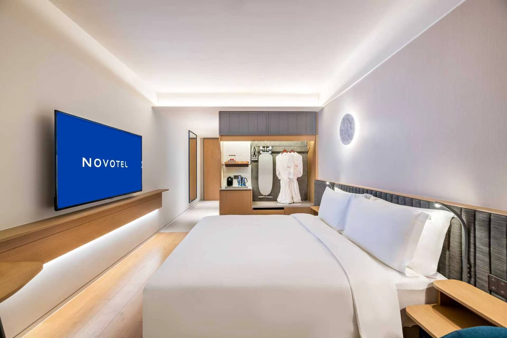 Una habitación de hotel con cama, televisión, bata y espejo.