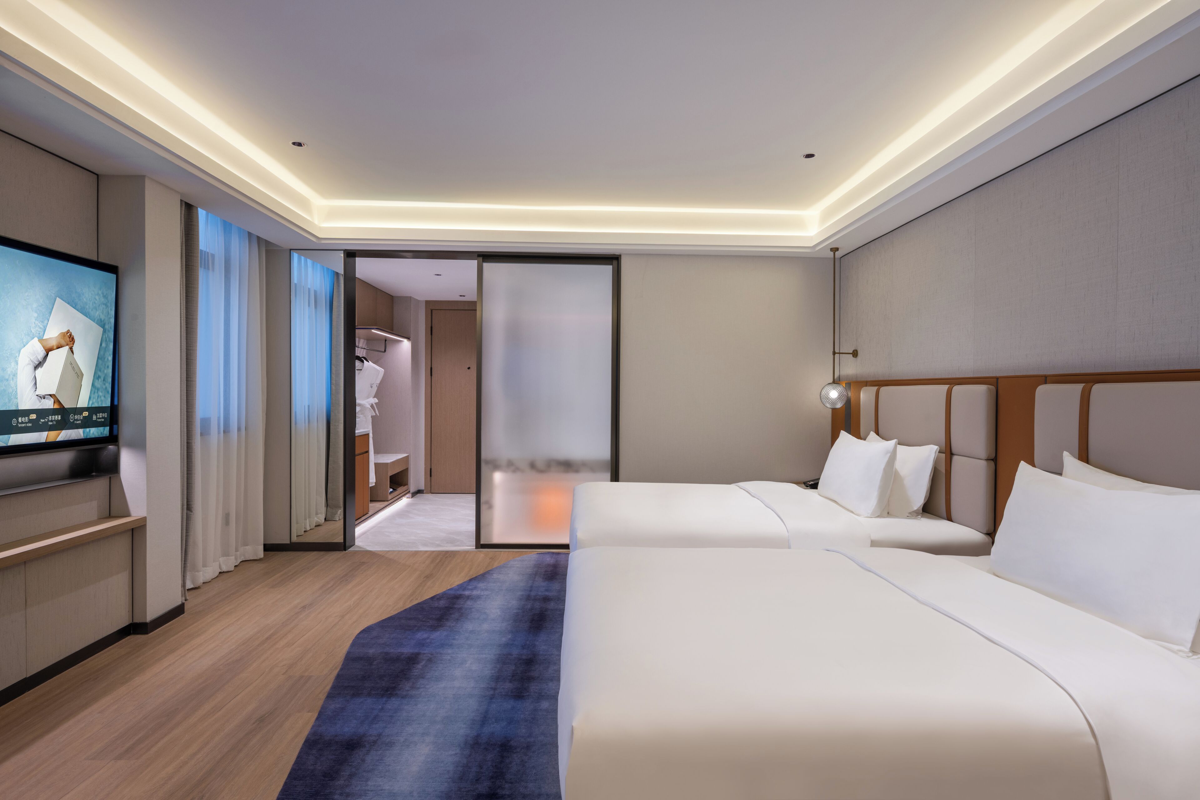 A modern hotel room with a large bed, a flat-screen TV, and a sliding door leading to a bathroom.