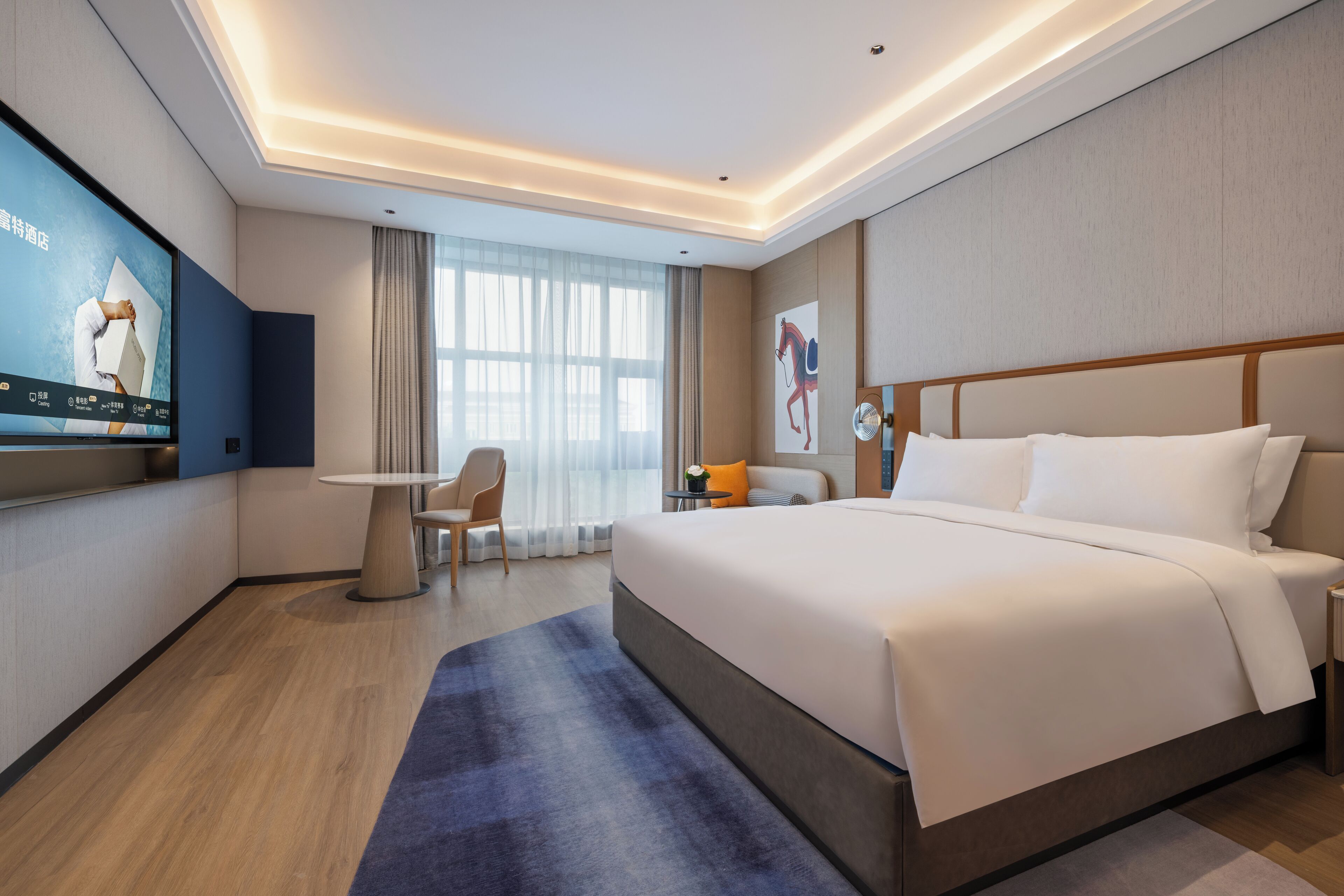 A modern hotel room with a large bed, a TV mounted on the wall, a desk, and a chair.