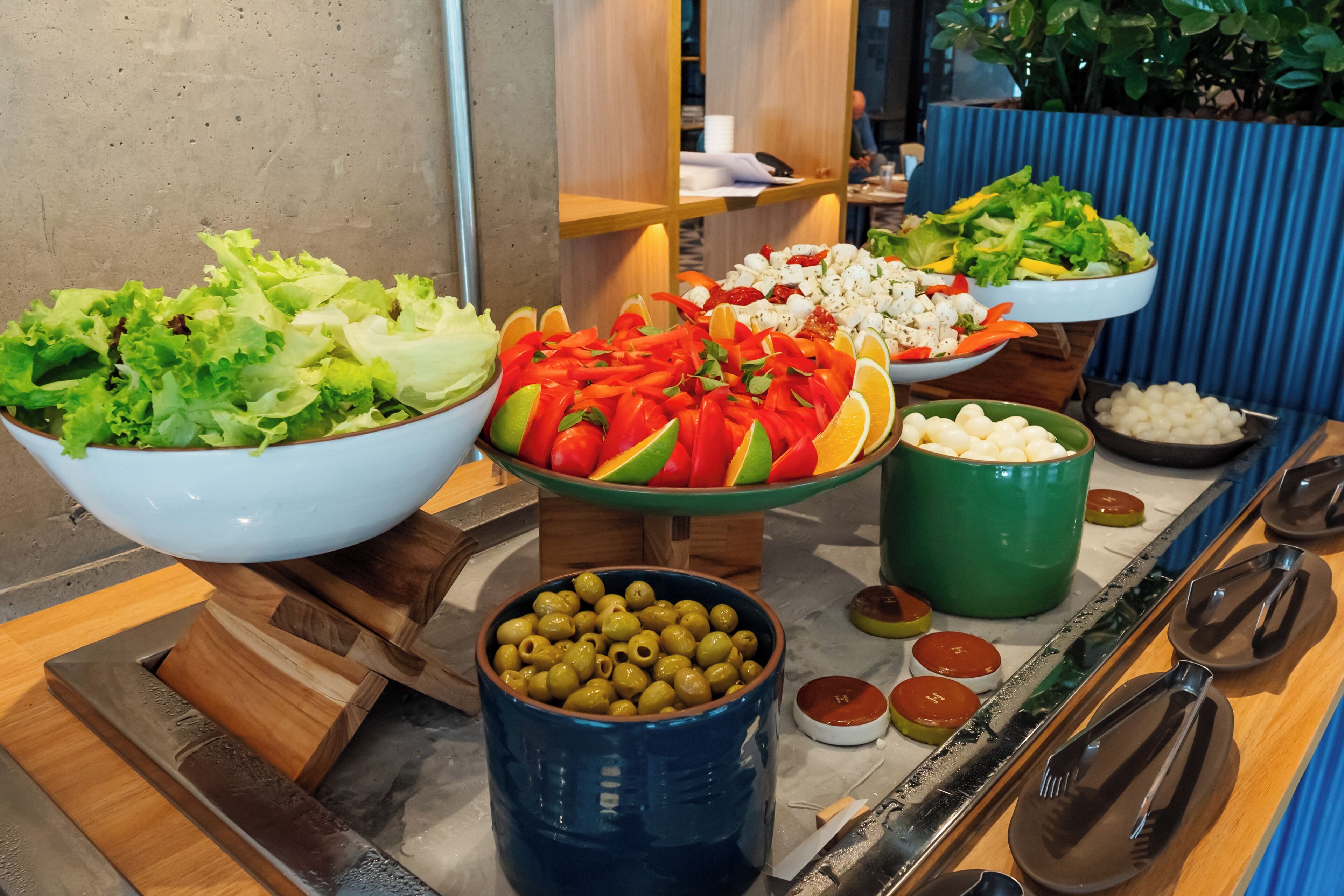 A buffet with various dishes including salads, fruits, and olives.