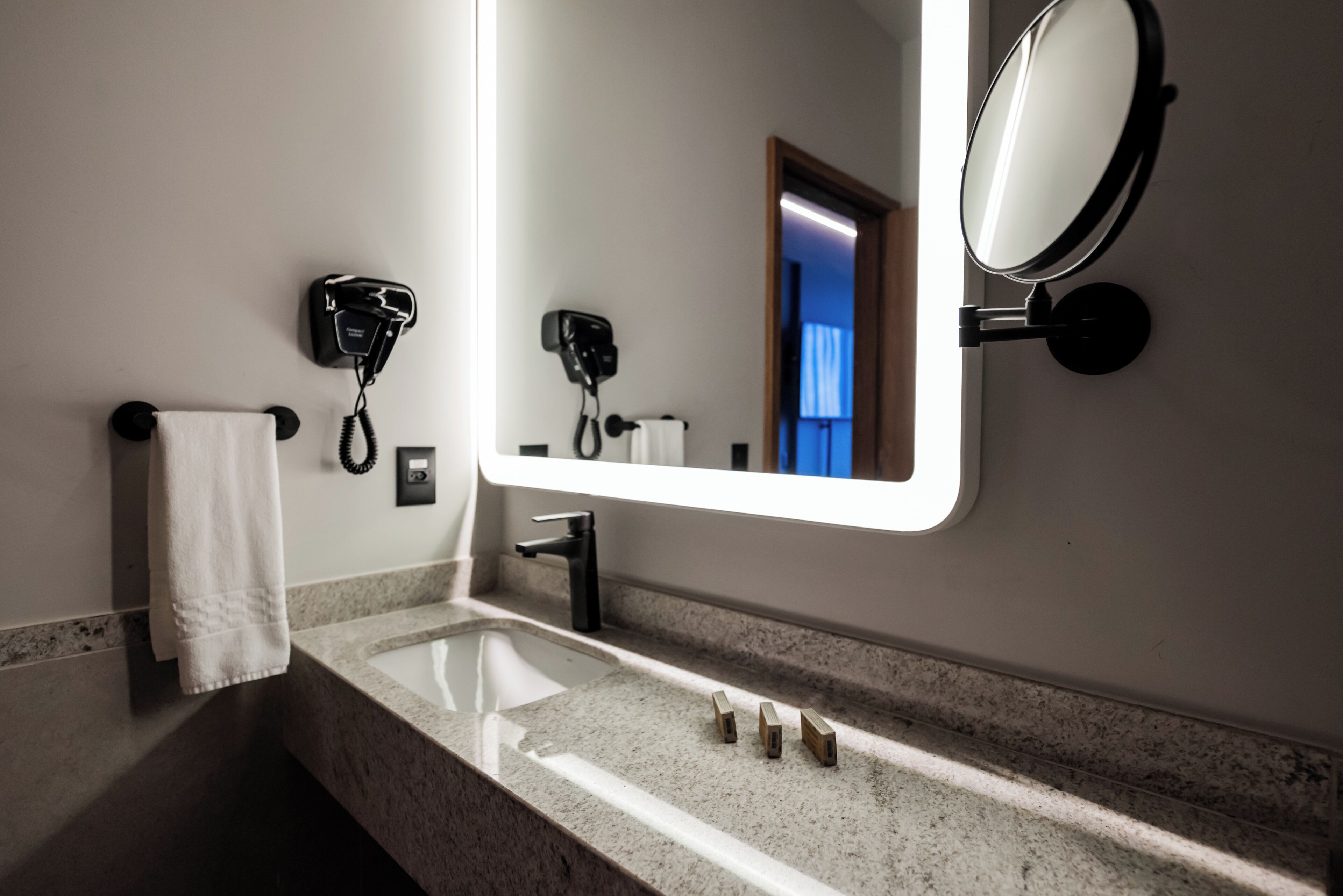 A bathroom with a sink, mirror, towel rack, and hairdryer.