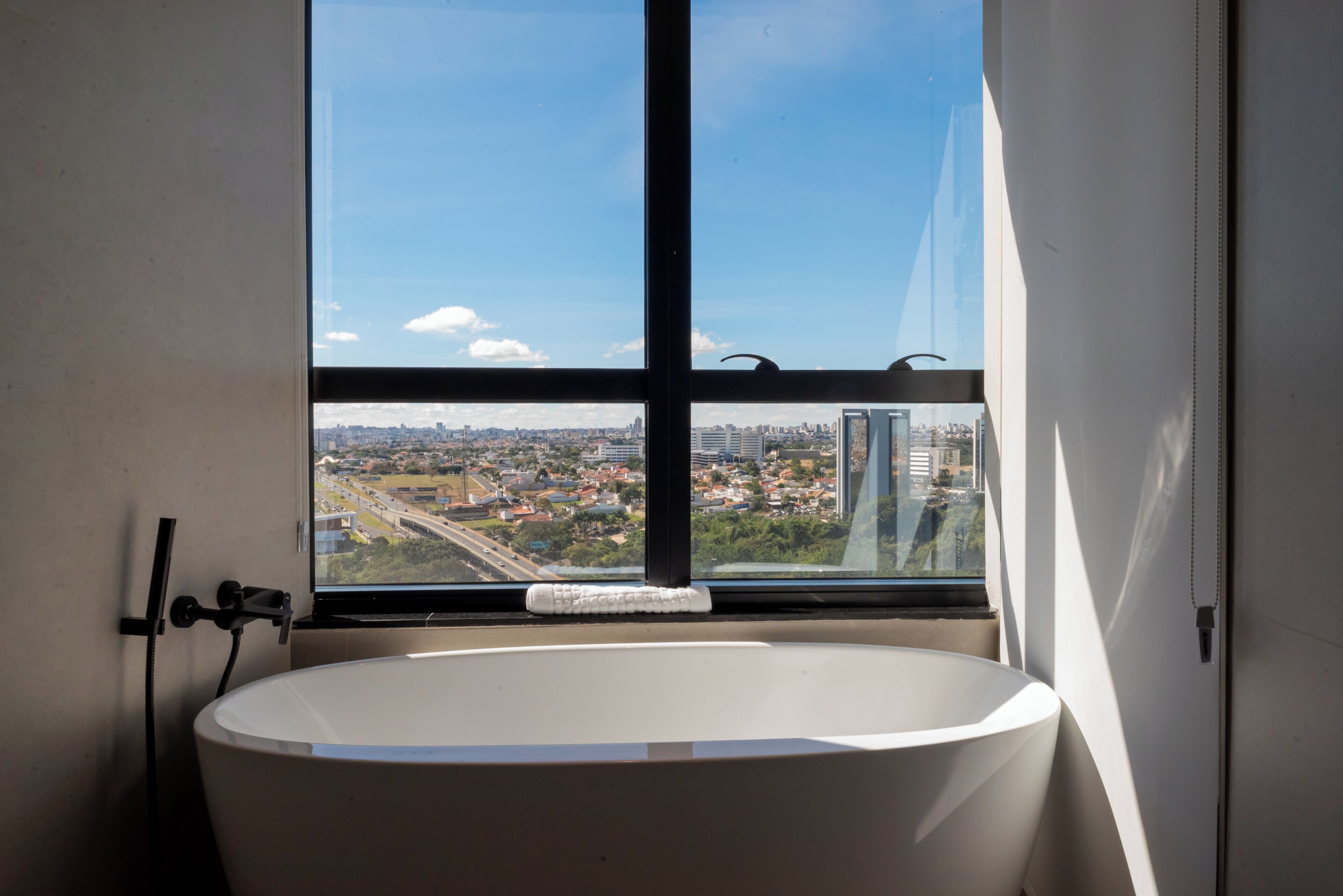 A bathroom with a bathtub, a window, and a view of a cityscape.