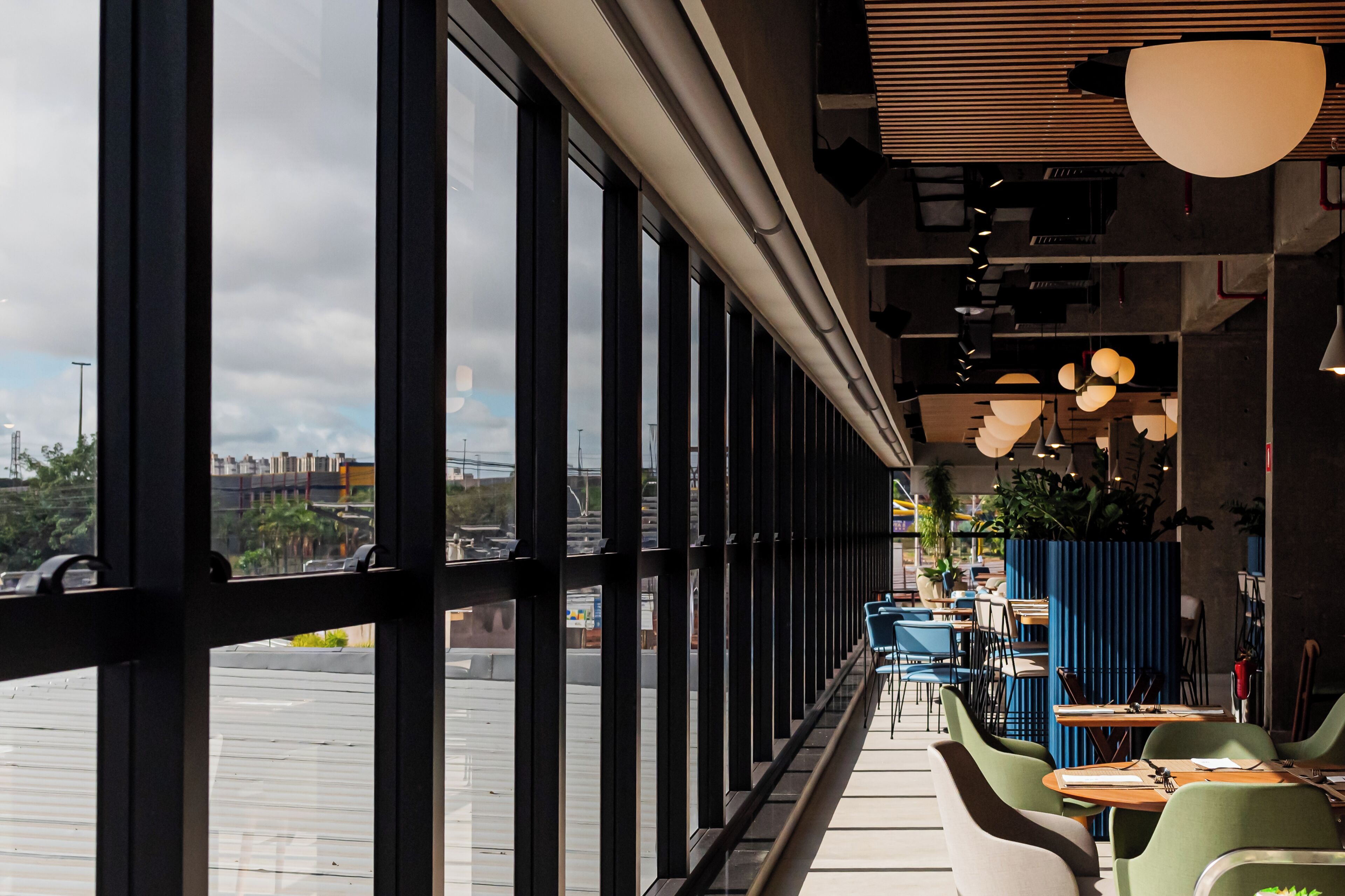 Un restaurante con amplios ventanales, mesas en el interior y vistas a la ciudad.