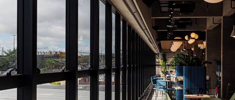 A restaurant with large windows, indoor seating, and a view of the city.