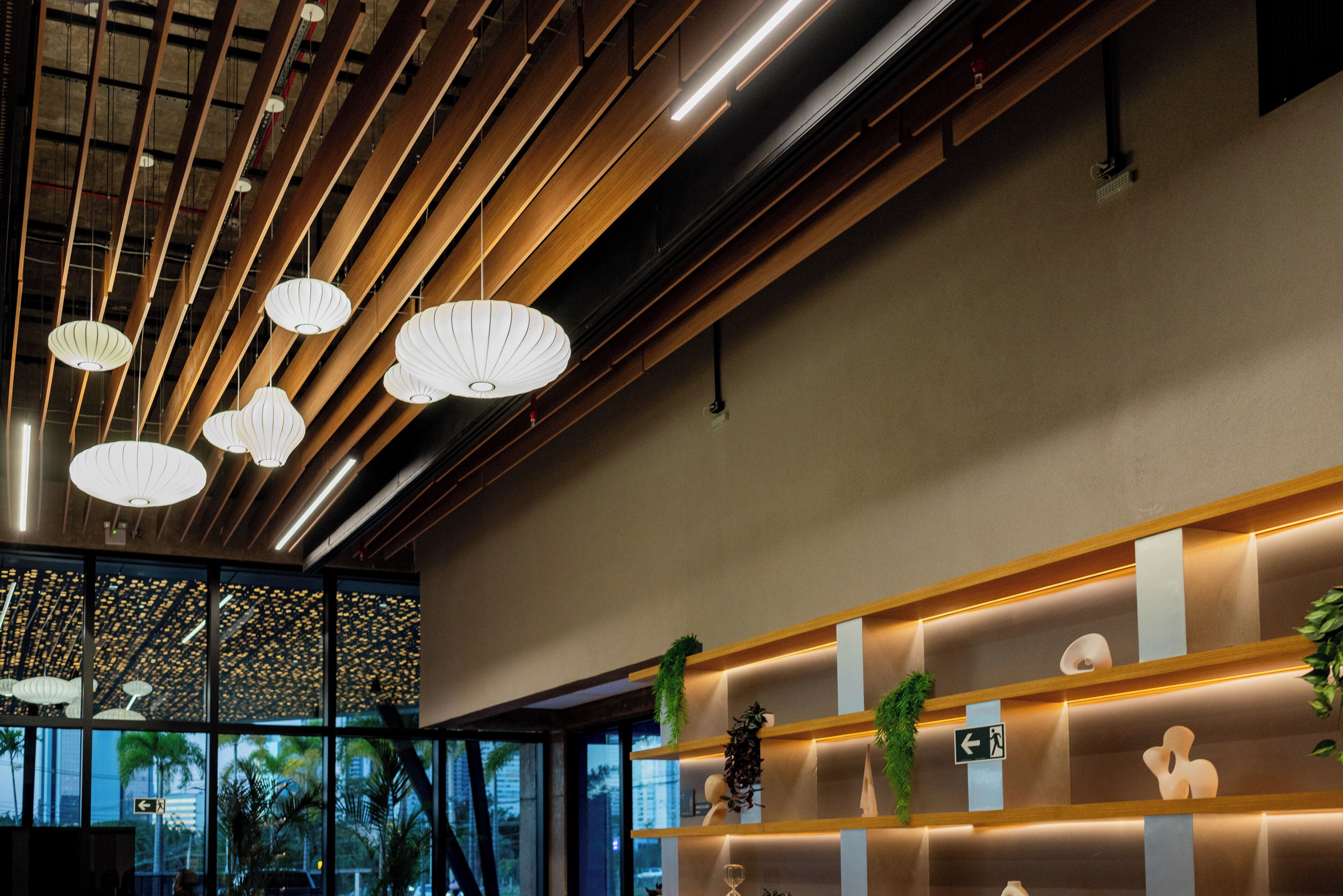 Un interior moderno con listones de madera en el techo y luces colgantes.