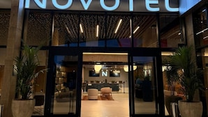 The exterior of a hotel with a modern design, featuring a prominent illuminated sign that reads "NOVOTEL". - Novotel Uberlândia (Uberlandia)
