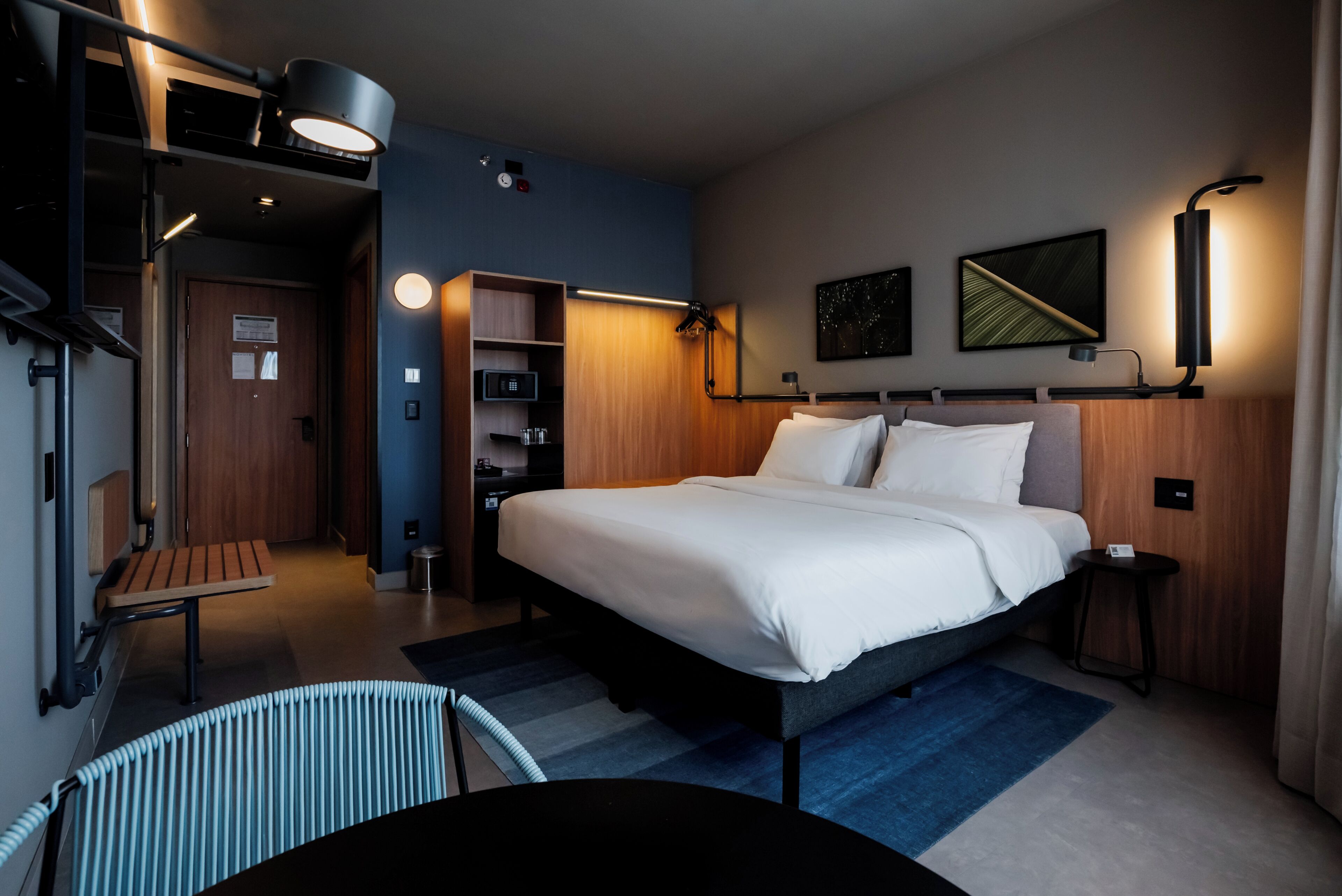 Una habitación de hotel moderna con una cama grande, un escritorio, una silla y una mesita.