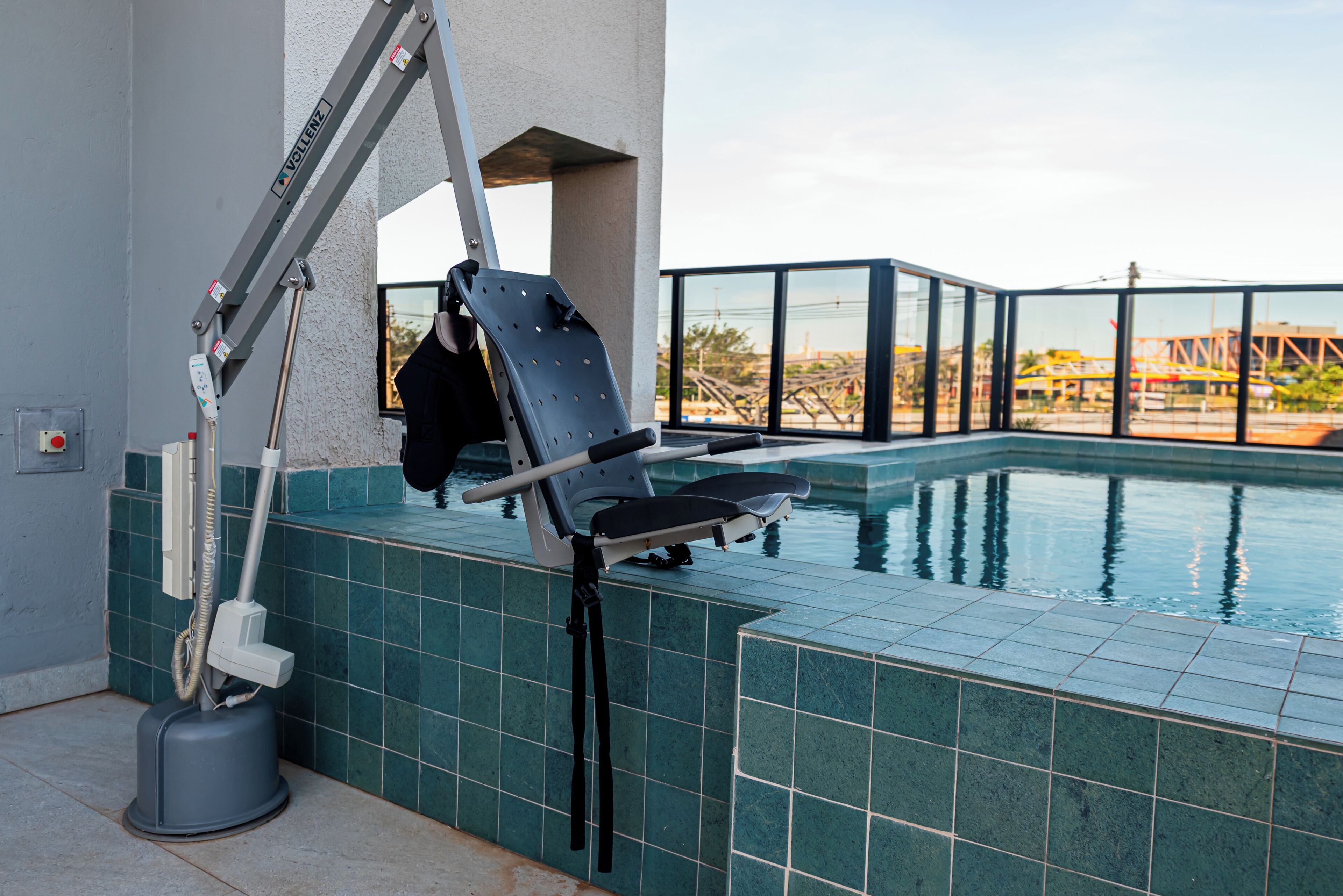 A poolside area with a chair and a pool lift.