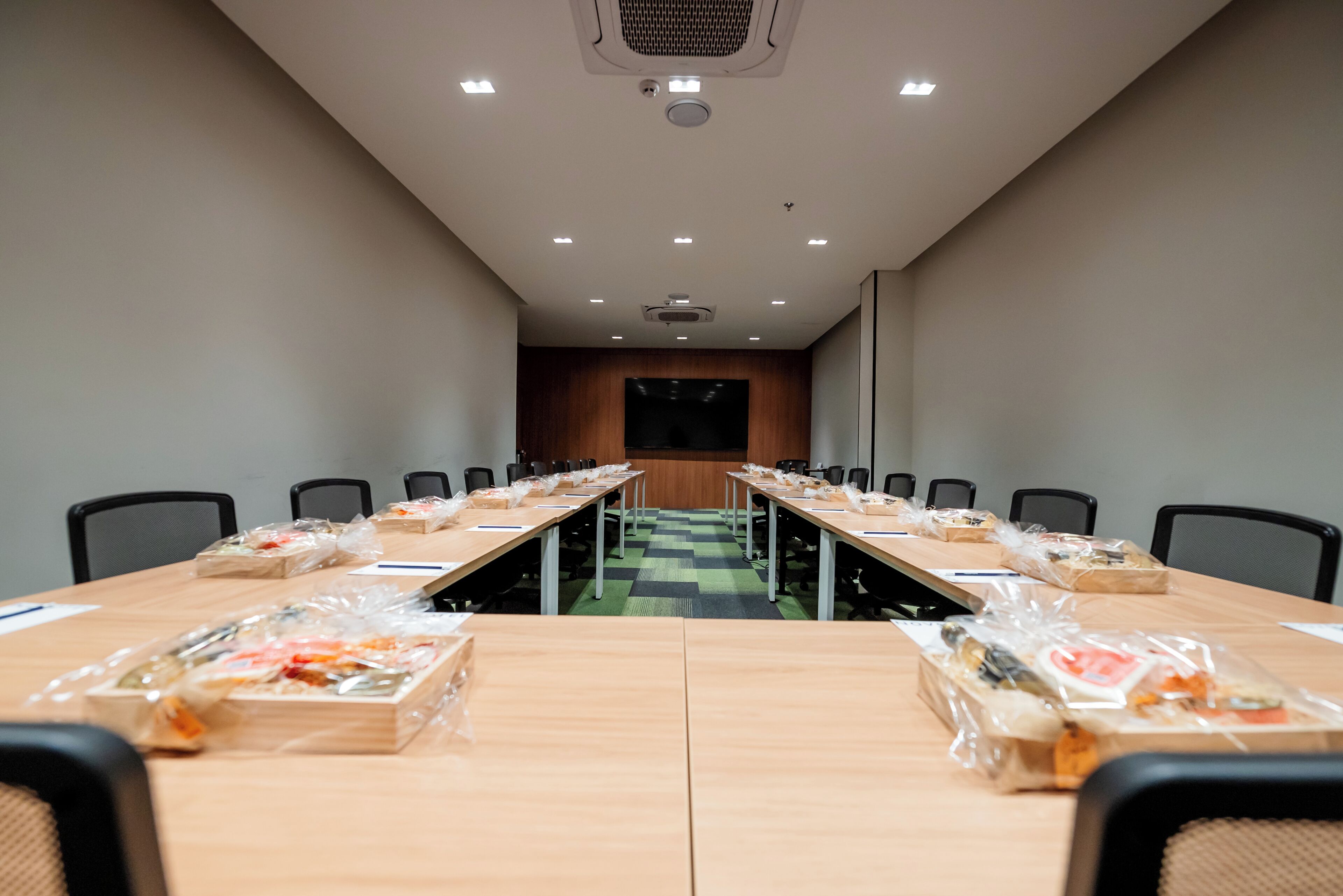A conference room with a long table, chairs, and a projector screen.