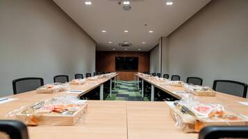A conference room with a long table, chairs, and a projector screen.