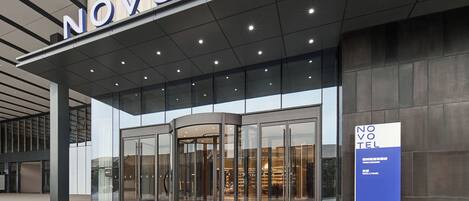 A hotel entrance with a revolving door, large glass windows, and a signboard.