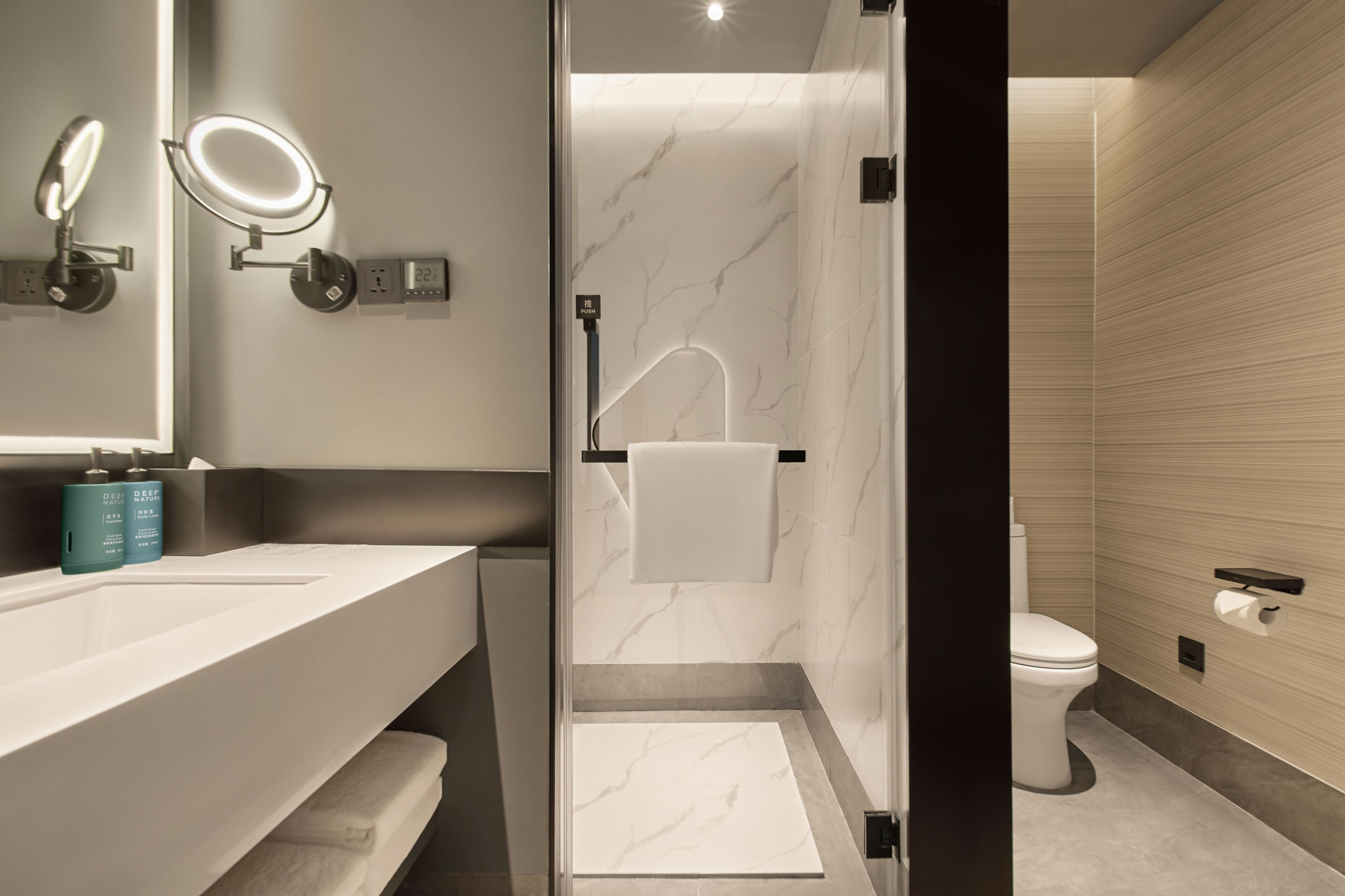 Un baño moderno con cabina de ducha de vidrio, un lavabo blanco y un inodoro.