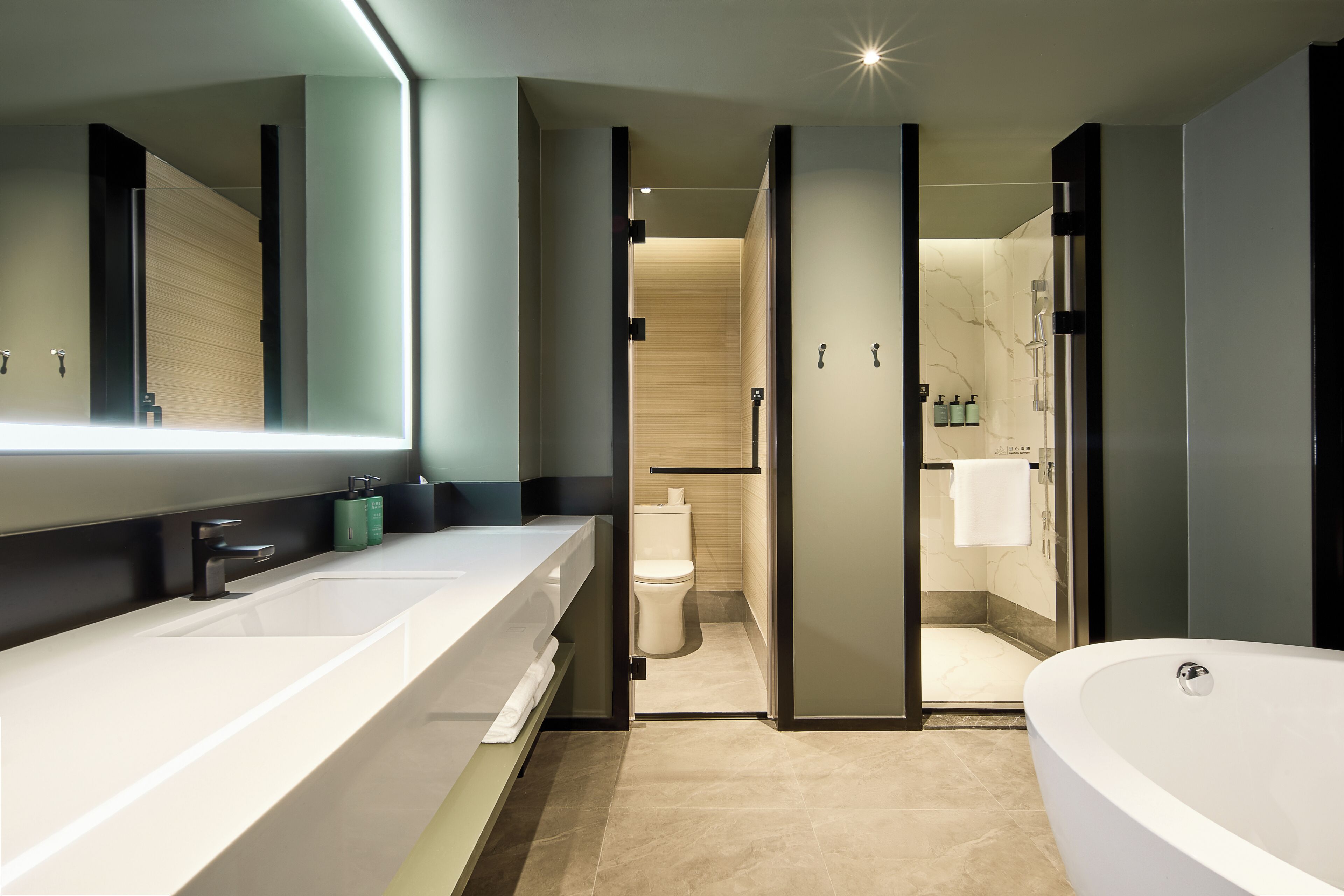 A modern bathroom with a large bathtub, a long sink, and a separate toilet area.