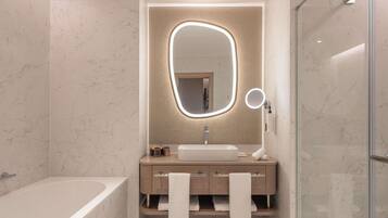 A modern bathroom with a marble floor, a freestanding bathtub, a vanity with a mirror, and a glass shower enclosure.